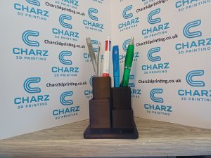 3D printed dual-compartment desk tidy holding pens and stationery on a wooden desk with branded Charz 3D Printing background