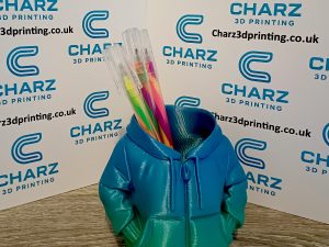 3D printed hoodie pen holder with colourful gel pens inside on a branded Charz 3D Printing background