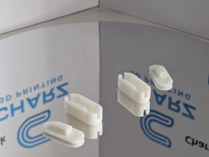 White 3D printed roller blind chain connectors displayed on mirrored surface